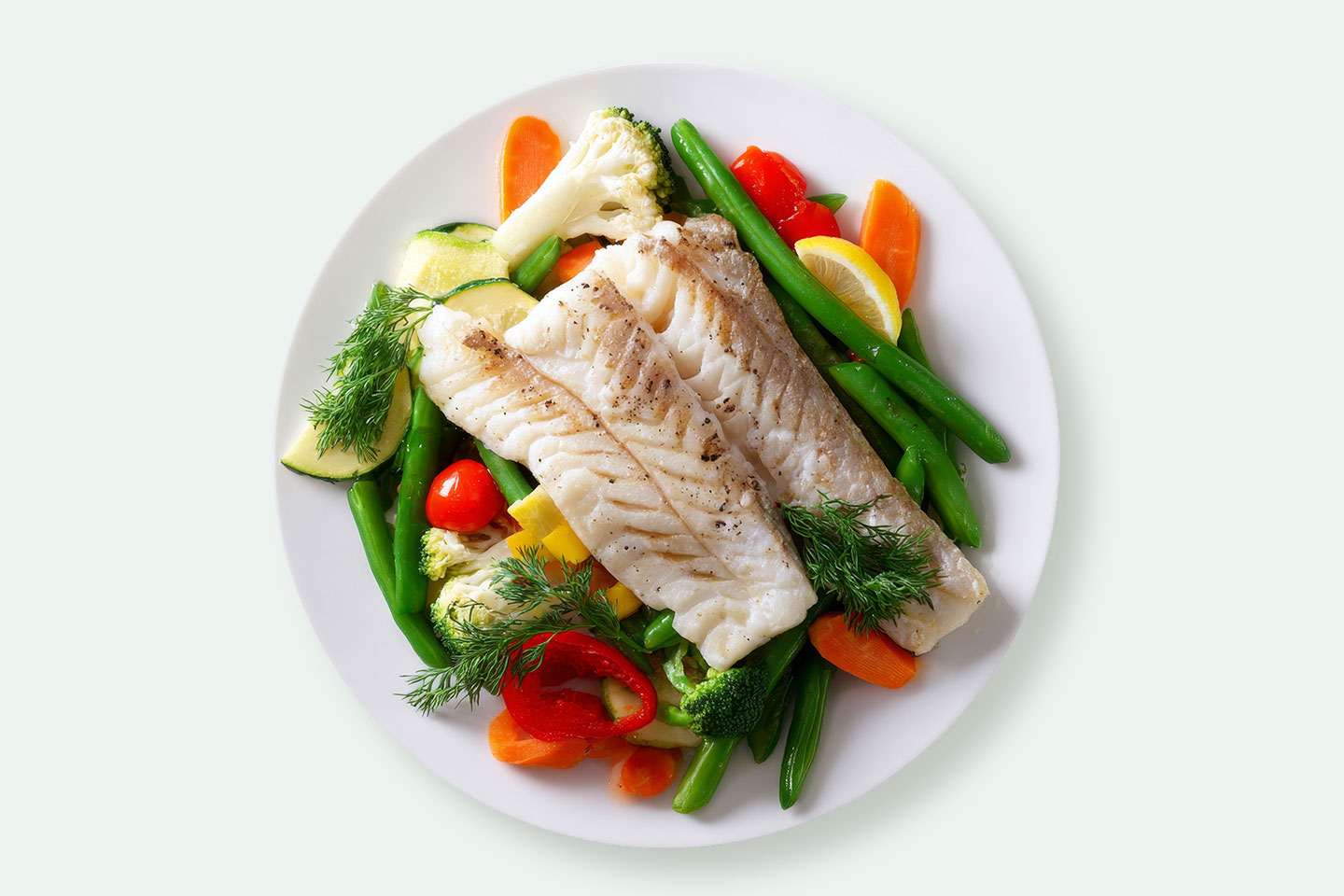 Slika pečenog filea bakalara sa svježim povrćem na tanjuru.